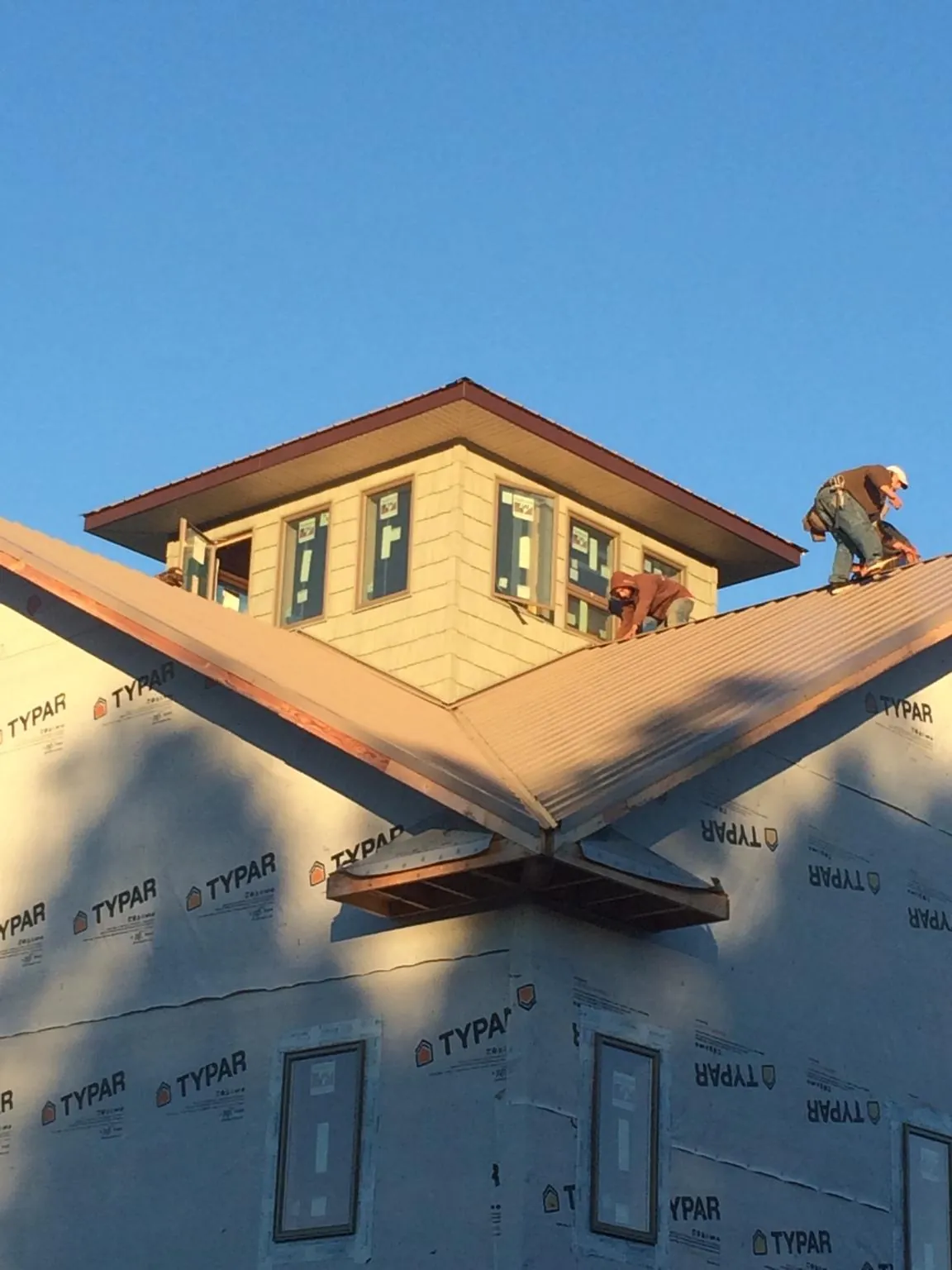Roofers working around a rooftop cupola on a new metal roof at sunset — Roof Waterproofing in Newtown by Roofing Brothers
